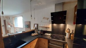 A modern kitchen with wooden cabinets, a black stove, and a stainless steel refrigerator. - Vars. Full-service center.  Private parking. Linens provided, beds made. (Vars)