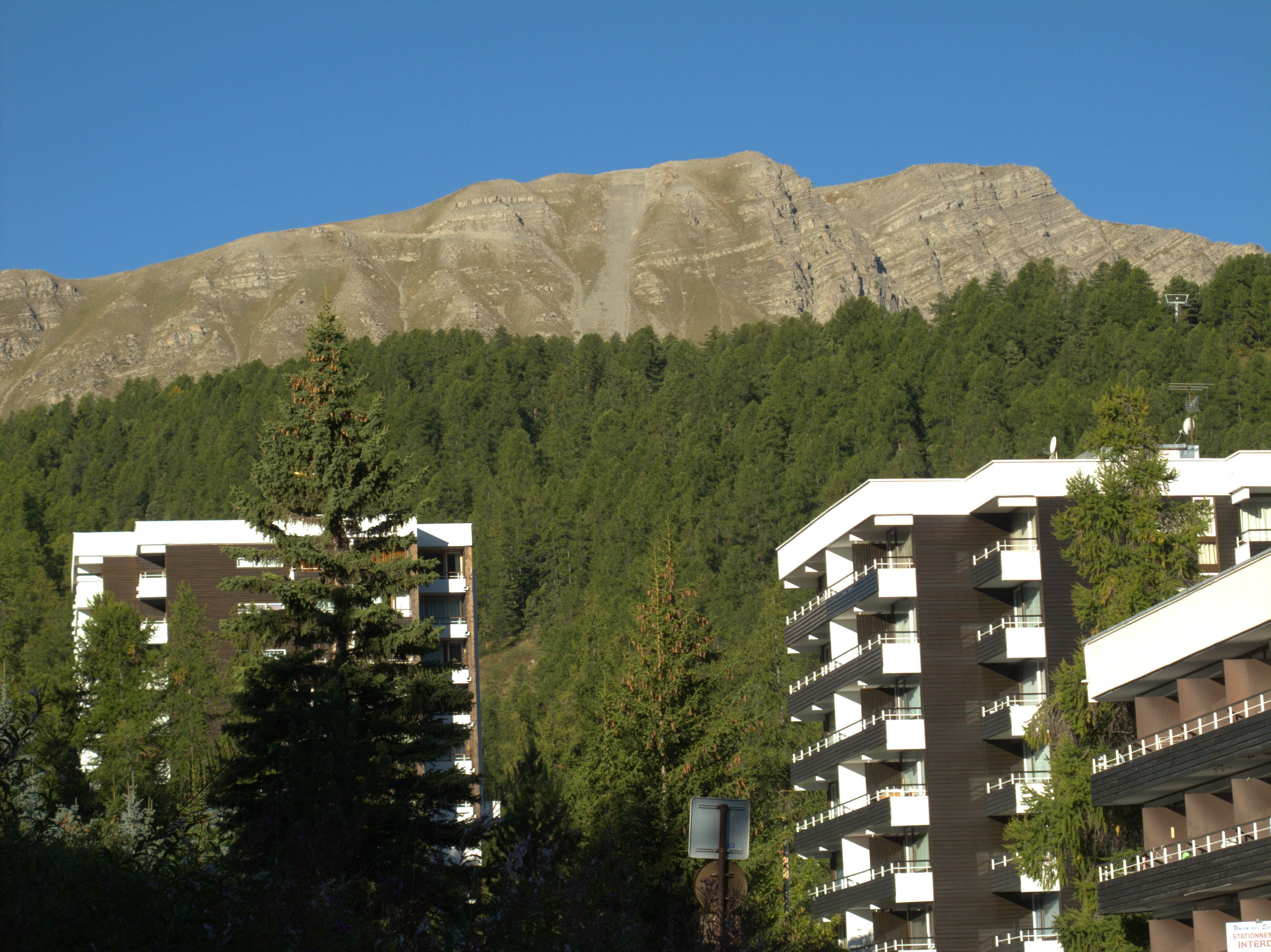 A modern building with multiple balconies and a mountain backdrop.