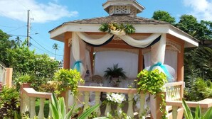 A gazebo with a white and blue color scheme, surrounded by lush greenery.
