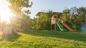 A playground with slides and swings, surrounded by trees and a wooden structure. - Self catering El Manantial del Fresno for 4 people (Hervás)
