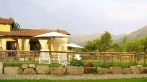 A house with a tiled roof, a fenced garden, and a mountainous backdrop. - Self catering El Manantial del Fresno for 4 people (Hervás)