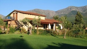 A two-story house with a red-tiled roof, a staircase leading to the upper floor, and a small porch with a railing. - Self catering El Manantial del Fresno for 4 people (Hervás)