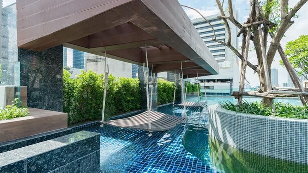 A rooftop infinity pool with a modern design, surrounded by greenery and urban buildings. - Luxurious Condo @Heart of Bangkok - Quiet location - Fast Wifi - 24 Hour Checkin (Bangkok)