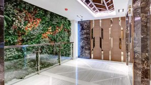 A modern interior with a glass railing, a green wall with plants, and a marble floor. - Luxurious Condo @Heart of Bangkok - Quiet location - Fast Wifi - 24 Hour Checkin (Bangkok)