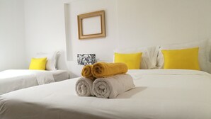 A hotel room with two beds, white bedding, and yellow pillows.