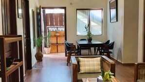 A spacious living area with a dining table and chairs, a sofa, and a bookshelf.