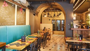 L’intérieur d’un restaurant avec des tables en bois, des banquettes bleues rembourrées et un sol carrelé.