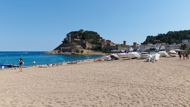 A beach with boats, a castle-like structure, and a clear blue sky. - DESCONNECTAR - Tossa de Mar (Tossa de Mar)