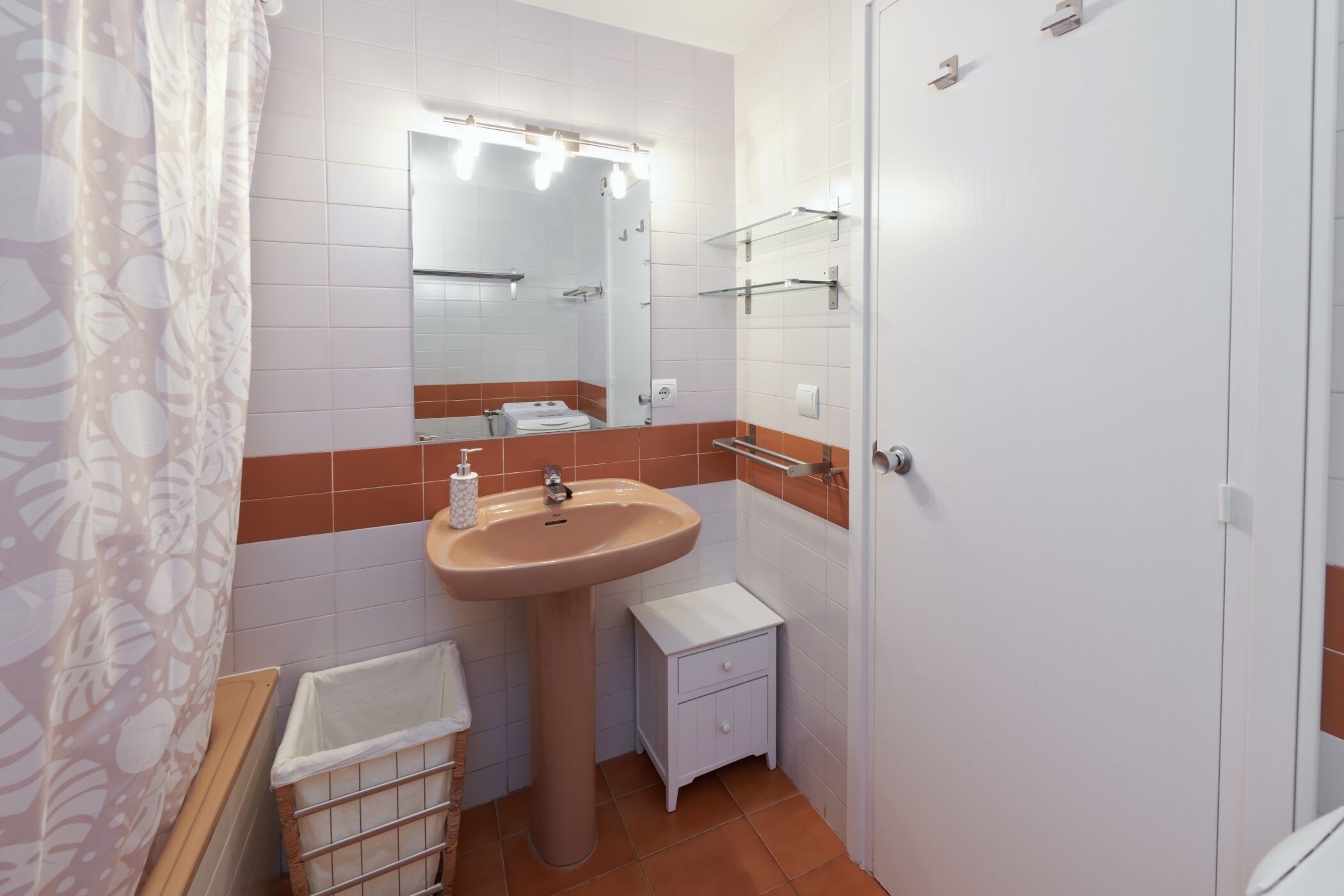 A bathroom with a sink, mirror, and storage shelves.