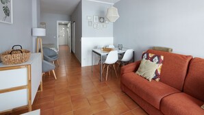 A modern living room with a sofa, a dining table with chairs, and a kitchen area in the background. - DESCONNECTAR - Tossa de Mar (Tossa de Mar)