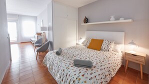 A bedroom with a large bed, a chair, a desk, and a shelf with decorative items. - DESCONNECTAR - Tossa de Mar (Tossa de Mar)
