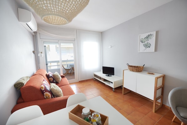 A modern living room with a sofa, TV, and a small table with a tray.