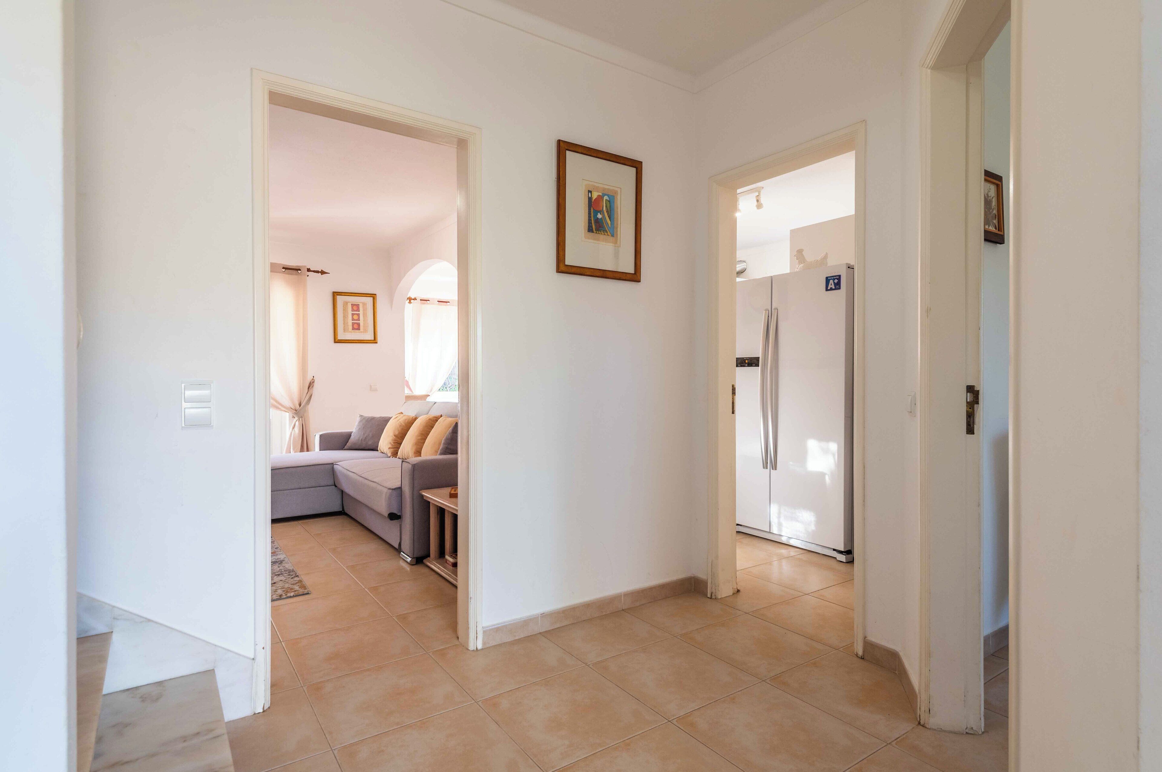 A hallway leading to a living area with a sofa and a refrigerator.