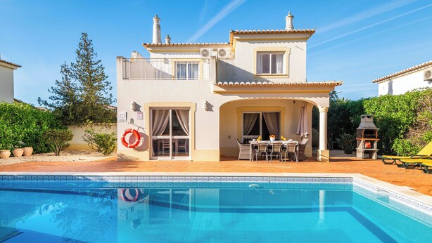 A two-story house with a swimming pool in front. - Villa Oásis, Piscina Privada, Ténis, Jacuzzi e Piscina Aquecida do Condomínio! (PortimÃ£o)