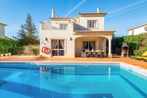 A two-story house with a swimming pool in front. - Villa Oásis, Piscina Privada, Ténis, Jacuzzi e Piscina Aquecida do Condomínio! (PortimÃ£o)