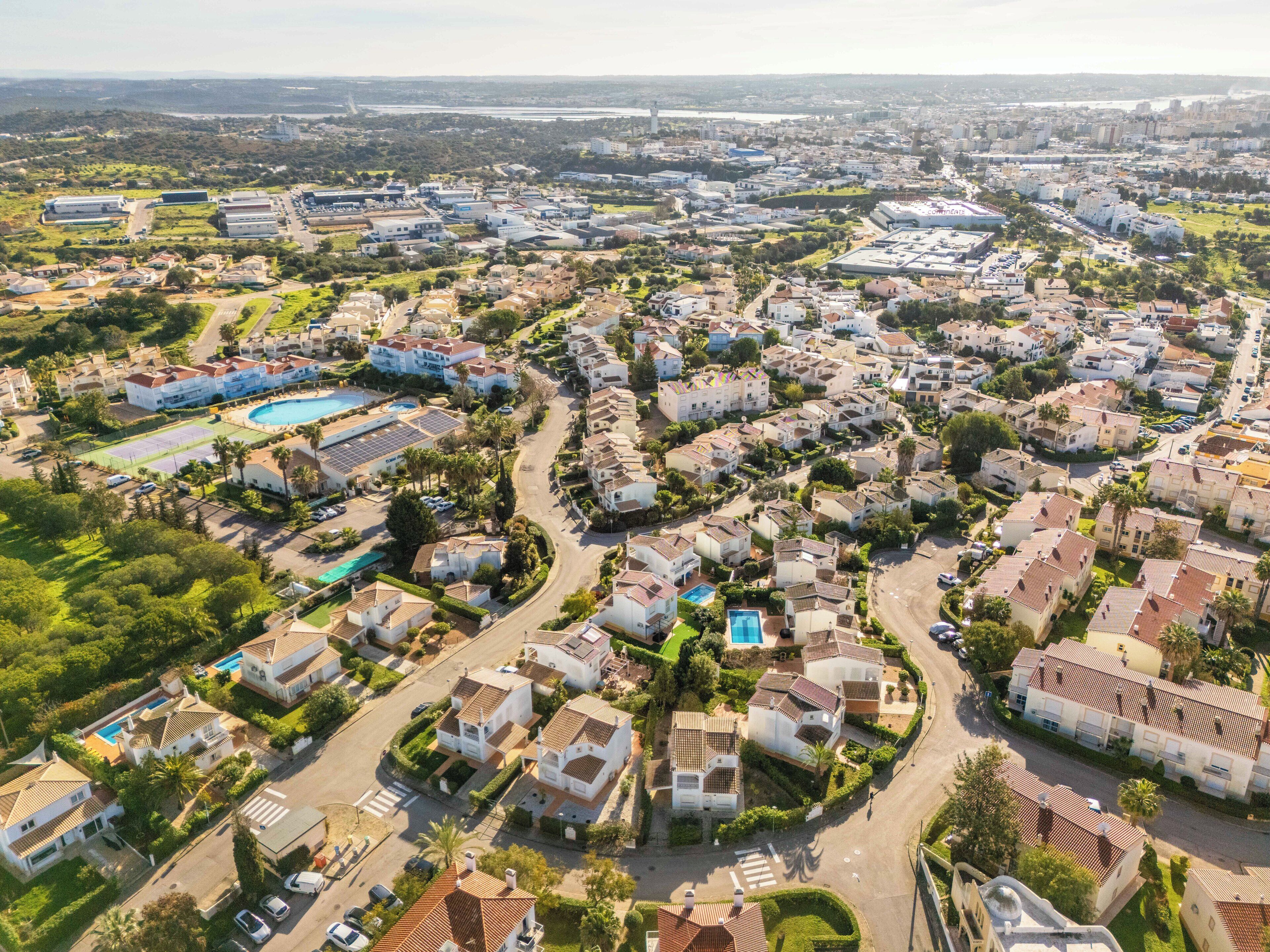 An aerial view of a residential area with houses, roads, and a swimming pool.