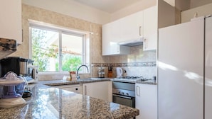 A modern kitchen with granite countertops, white cabinets, a built-in oven, and a stainless steel range hood. - Villa Oásis, Piscina Privada, Ténis, Jacuzzi e Piscina Aquecida do Condomínio! (PortimÃ£o)