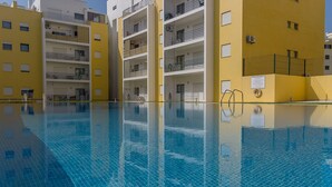 Una piscina con acqua cristallina, circondata da edifici gialli con balconi e finestre.