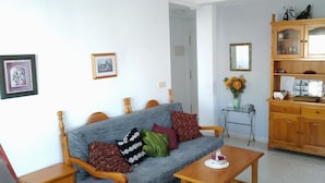 A living room with a grey sofa, wooden cabinet, and a small table with a vase. - Beautiful apartment in Torrevieja (Torrevieja)