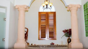 Una entrada imponente con un gran arco de entrada, flanqueado por altas columnas, y una ventana con contraventanas de madera encima.