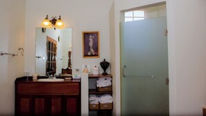 Un baño con tocador de madera, un espejo, una obra de arte enmarcada y una puerta con vidrio esmerilado.