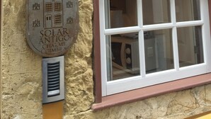 Una ventana con marco blanco y un interior rojo, adosada a una pared amarilla con textura.