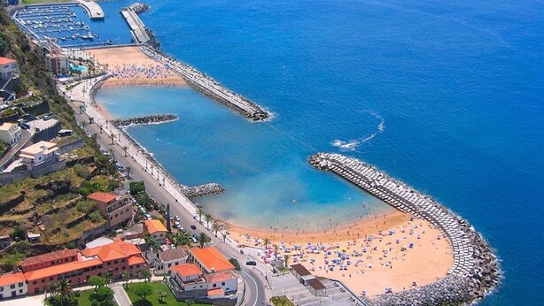 An aerial view of a coastal area with a beach, a marina, and residential buildings. - Apartment Casa Anny 2 (Madeira)