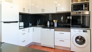 A modern kitchen with white cabinets, a dishwasher, a microwave, and an oven. - Apartment Casa Anny 2 (Madeira)