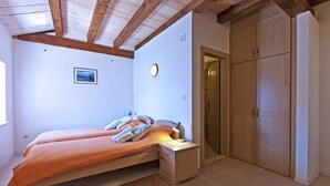 Een slaapkamer met een bed, nachtkastjes, een kledingkast en een plafond met houten balken.