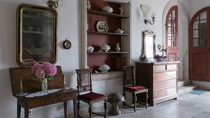 Een kamer met een houten dressoir, een spiegel en planken met decoratieve objecten.