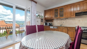Une cuisine avec des meubles en bois, un four à micro-ondes et une cuisinière. On y trouve une table à manger recouverte d’une nappe à pois et deux chaises.