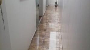 A hallway with a tiled floor, white walls, and a potted plant.