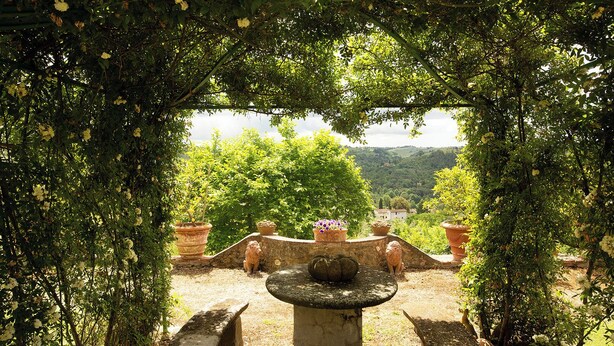 Un jardin agrémenté d’une fontaine en pierre, de pots en terre cuite et d’un banc.