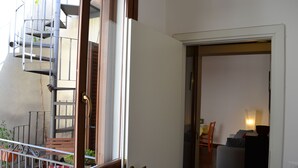 Ein Zimmer mit Holztür, einer Treppe, einem kleinen Tisch und einem Stuhl.
