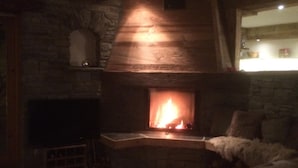 A cozy living room with a stone fireplace, a television, and a comfortable seating area. - Les Arcs skiing: Charming chalet in an idyllic location minutes from chair lift (Villaroger)