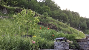 A stone bridge with an arched entrance, surrounded by lush greenery and wildflowers. - Les Arcs skiing: Charming chalet in an idyllic location minutes from chair lift (Villaroger)