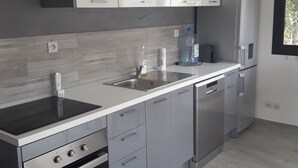 Une cuisine moderne avec des meubles gris, un lave-vaisselle en acier inoxydable et un four encastré.