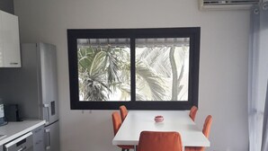 Une cuisine moderne avec des meubles blancs, un lave-vaisselle en acier inoxydable et une table à manger blanche, assortie de chaises orange.