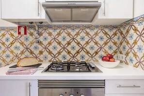 A kitchen with a gas stove, a bread loaf, and a bowl of apples.