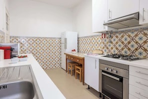 A compact kitchen with a gas stove, oven, and white cabinets.