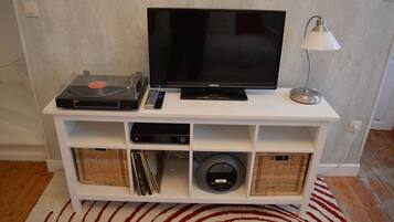 Un meuble de rangement blanc pour appareils électroniques, avec un téléviseur à écran plat, une platine vinyle et une lampe.