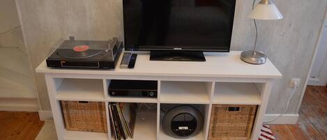 A white entertainment unit with a flat-screen TV, a turntable, and a lamp.