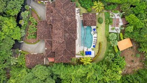 Vue aérienne d’un complexe hôtelier comprenant plusieurs bâtiments, une piscine et une végétation luxuriante.