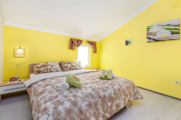 A bright yellow room with a bed, a bedside table with a lamp, and a window with curtains. - Villa Volcera *****  (Bakar)