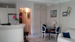 A modern kitchen with white cabinets, a marble countertop, and a dining area with a table and chairs. - Residential area 5 minutes from the beach  (Cannes)