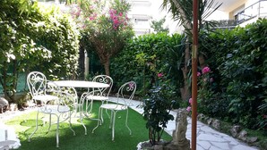 A garden with a table and chairs, surrounded by lush greenery and flowering plants. - Residential area 5 minutes from the beach  (Cannes)