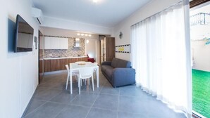 Un appartement moderne comprenant un coin repas, une cuisine et un salon avec un canapé et une grande fenêtre.