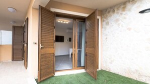 Un intérieur moderne avec un mur en pierre, une entrée avec une porte en verre et une salle de bain visible.