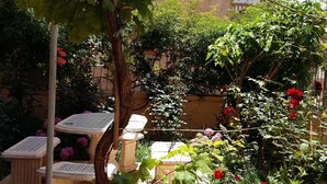 A garden with a pergola, tables, and various plants including roses.