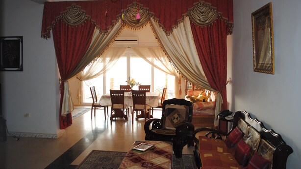 A room with a dining area, a sofa, and a chandelier.